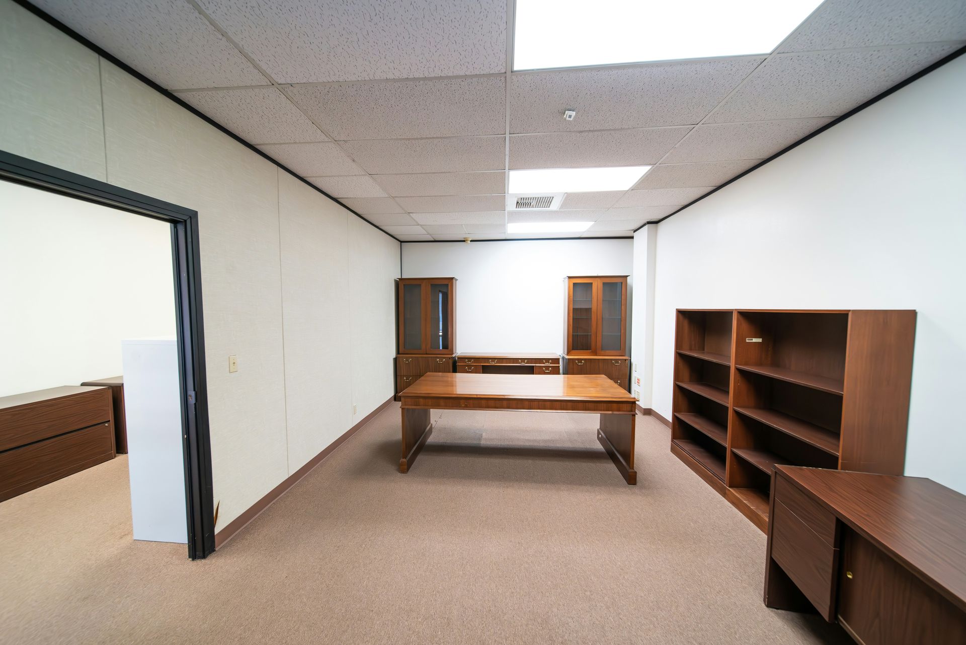 a room with a desk and a book shelf